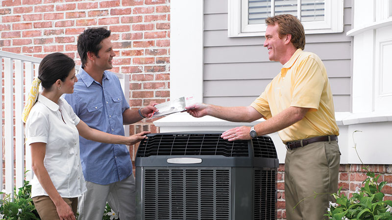 service tech outside with couple with hvac unit