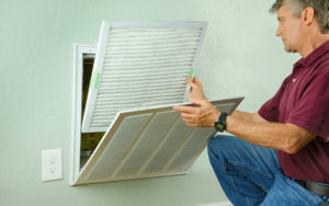 Home Owner Putting New Air Filter On Air Conditioner